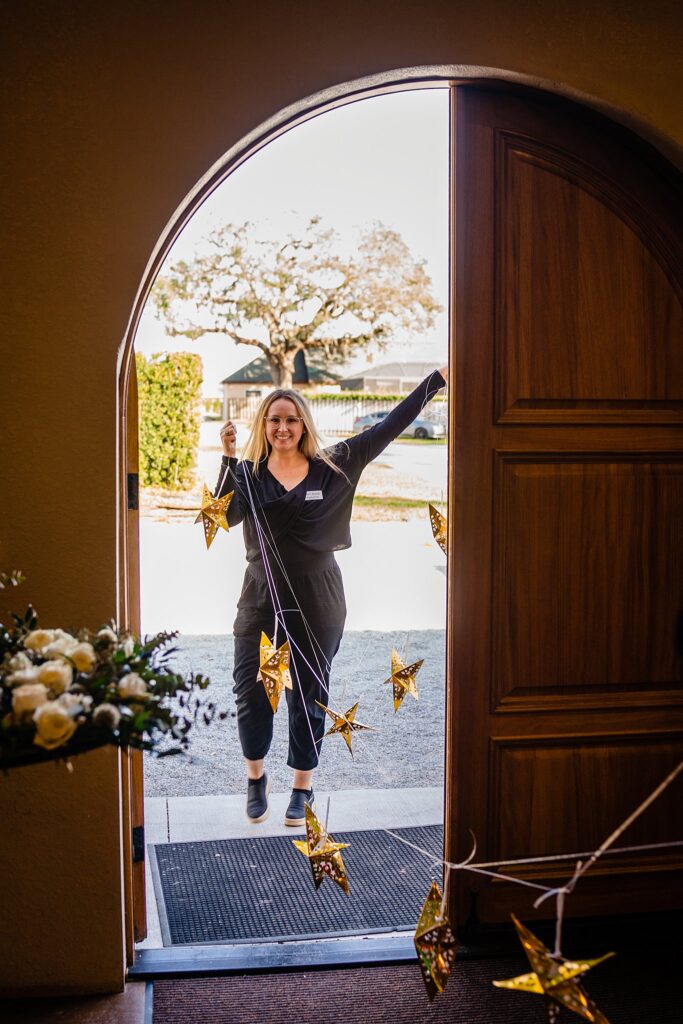 Bakers Ranch coordinator bringing in gold star twinkle light decor through arched doorway by Ying Multimedia