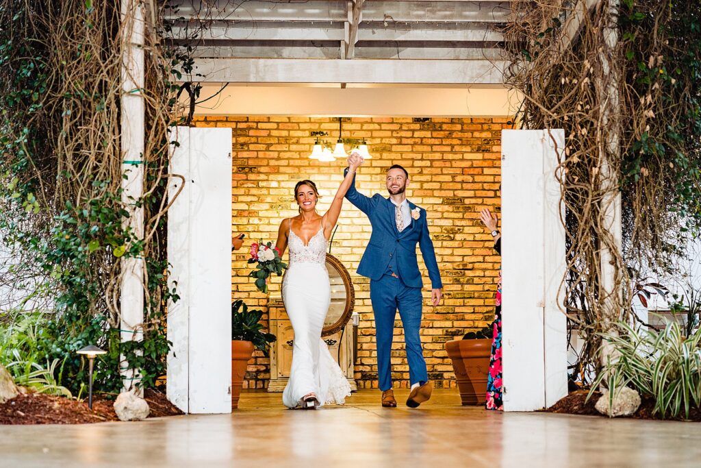 Bride and groom cheering as they enter the pavilion reception through the brick entryway at The Pavilion at Mixon Farms