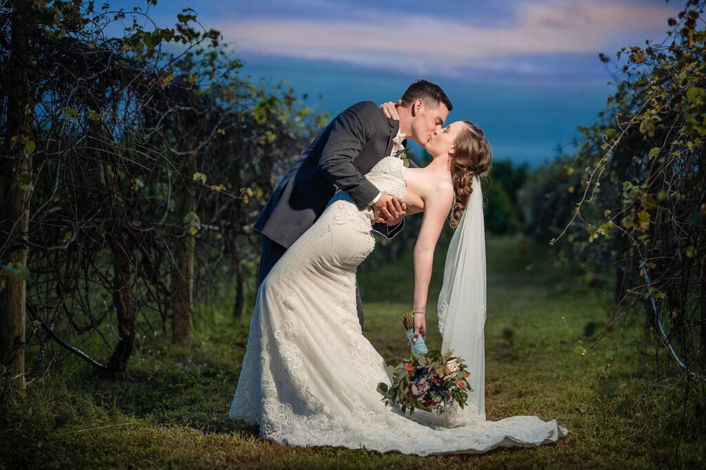 Bride and groom kissing among the grapevines at the former vineyard at Mixon Farms, since removed and now parking