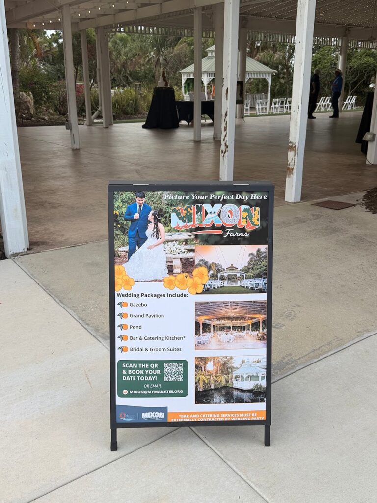 Manatee County sandwich board sign listing Mixon Farms wedding package inclusions, featuring photos by Ying Multimedia