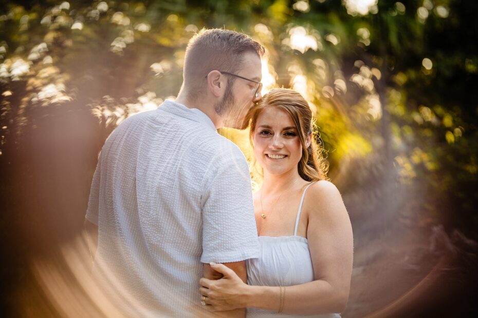 Bride smiling widely while groom kisses her temple at Dickson Azalea Park Orlando engagement session