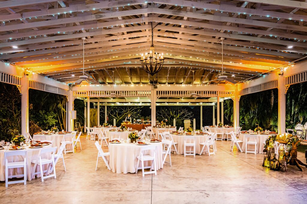 The pavilion set for a reception, string lights and chandelier overhead at The Pavilion at Mixon Farms.
