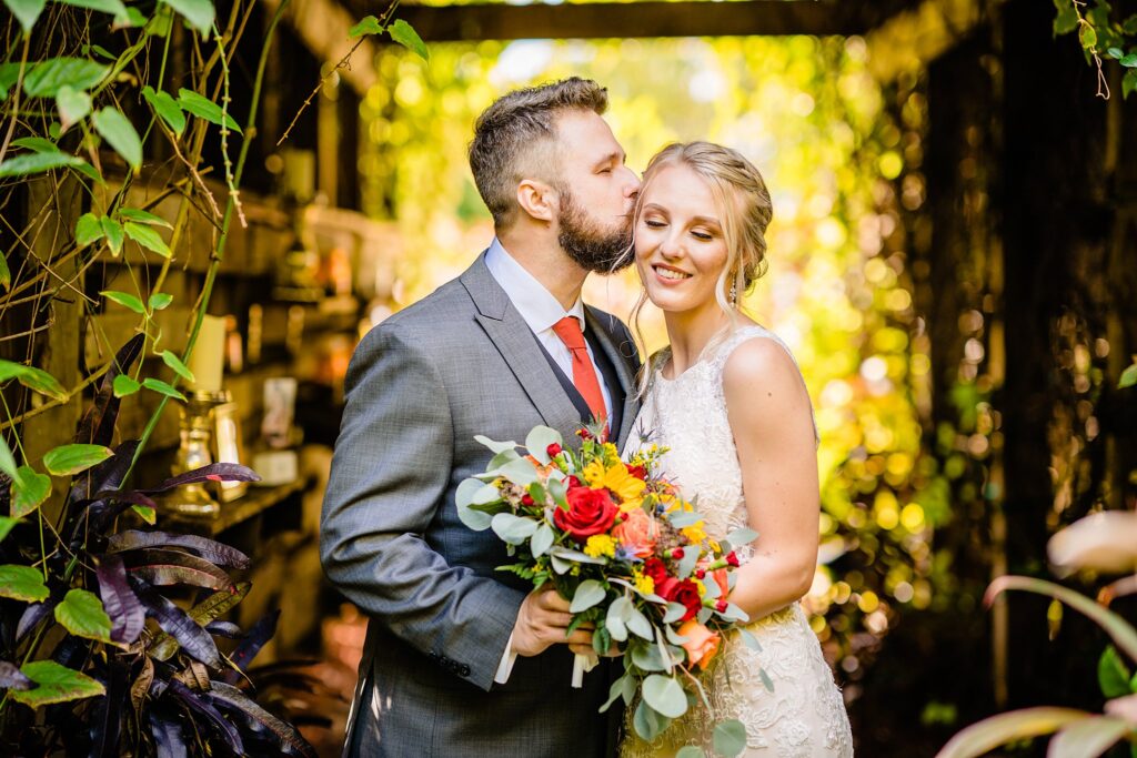 Groom kissing his bride on the cheek during their first look at The Pavilion at Mixon Farms