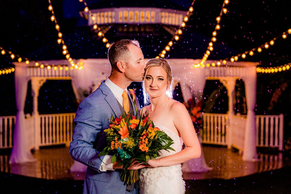 Bride and groom portrait in the rain with the lit gazebo behind them at The Pavilion at Mixon Farms