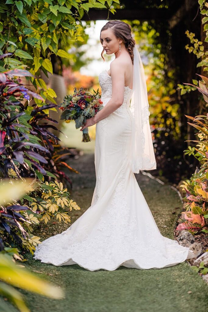 Bride looking back over her shoulder in a vine covered walkway at The Pavilion at Mixon Farms