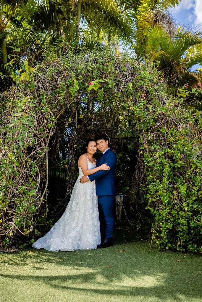 Bride and groom embracing under the palm arbor at The Pavilion at Mixon Farms