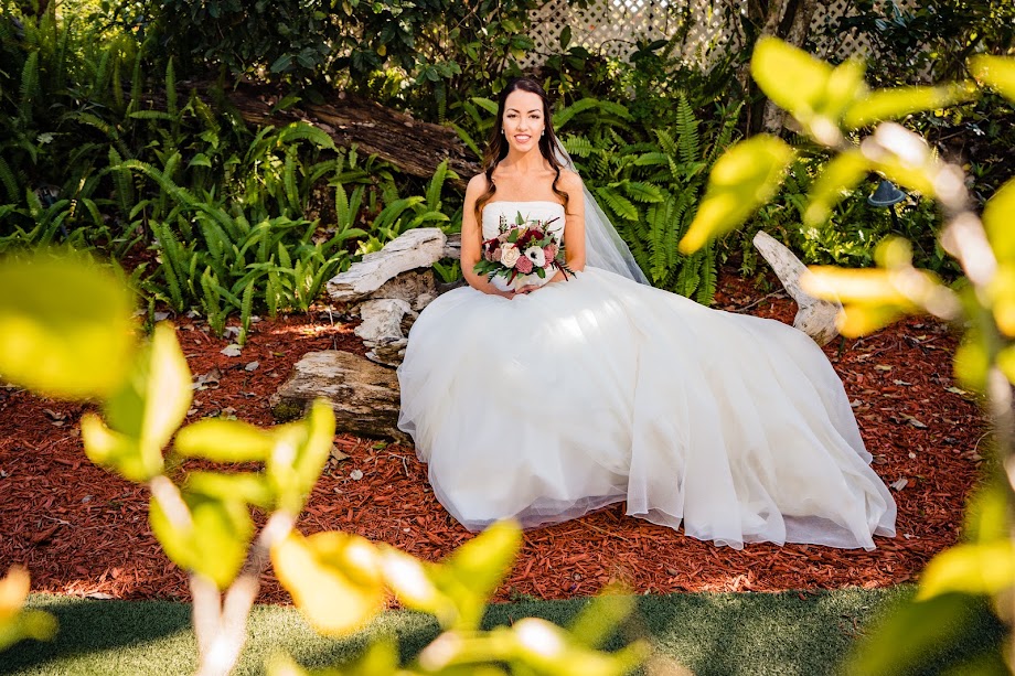 Bride seated on a driftwood bench along the wooded trail to the waterfall at The Pavilion at Mixon Farms